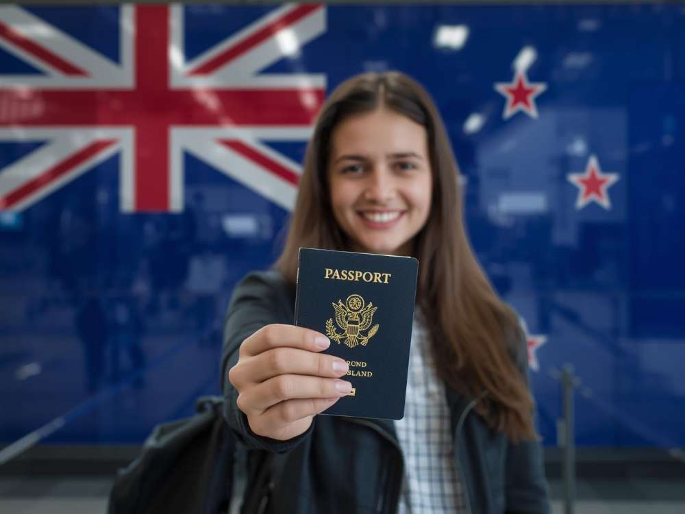 A student holding a passport in her hand showing excitement to study in Newzeeland.